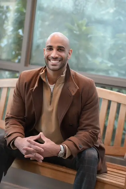 Jas Chahal seated on a bench, smiling